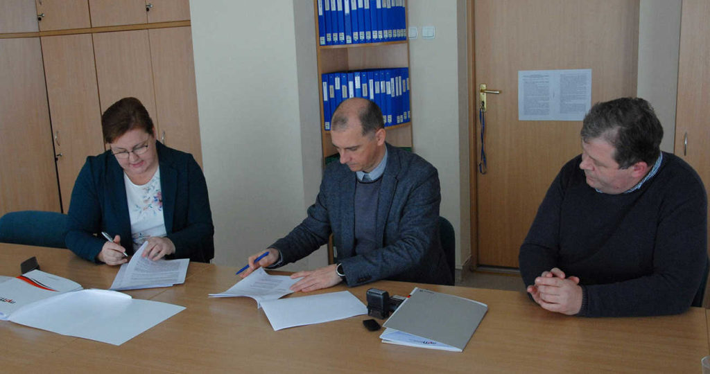 Trzy osoby podpisujące umowę w tym jedna kobieta pierwsza z lewej