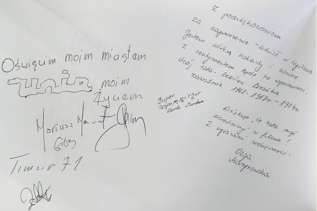 Zdjęcie przedstawia kartę papieru wraz z autografiami i wpisami do ksiegi pamiątkowej. 