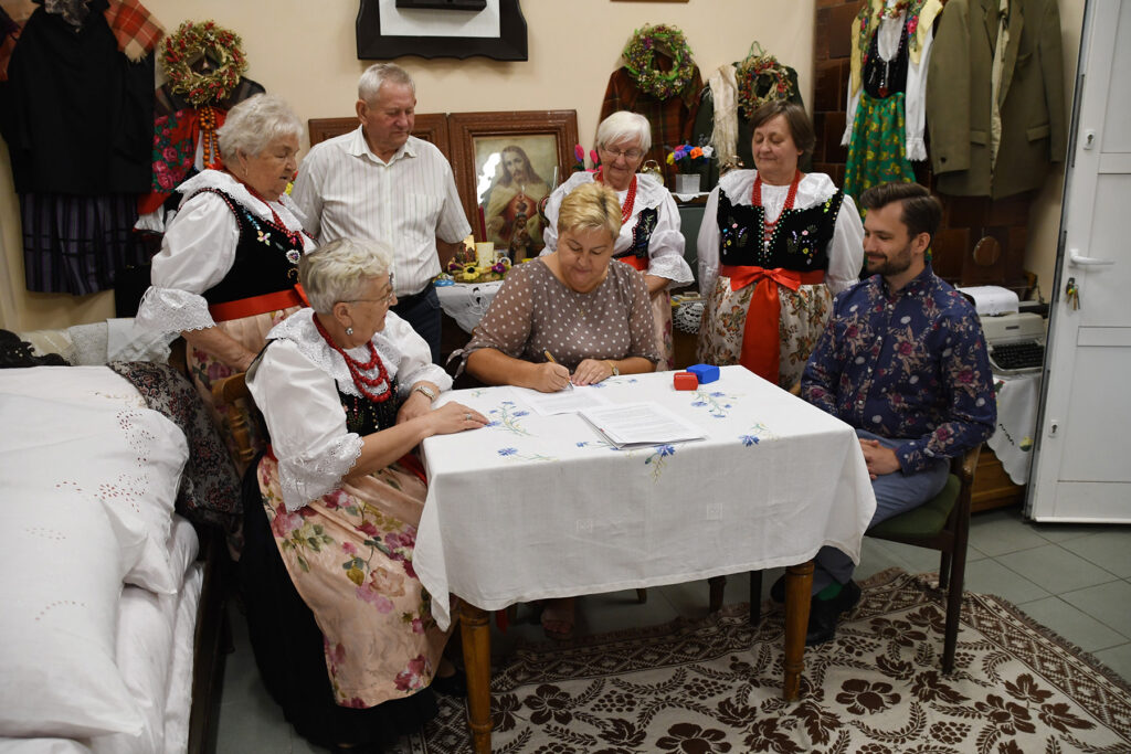 Ludzie siedzący przy stole w tradycyjnych strojach regionalnych.